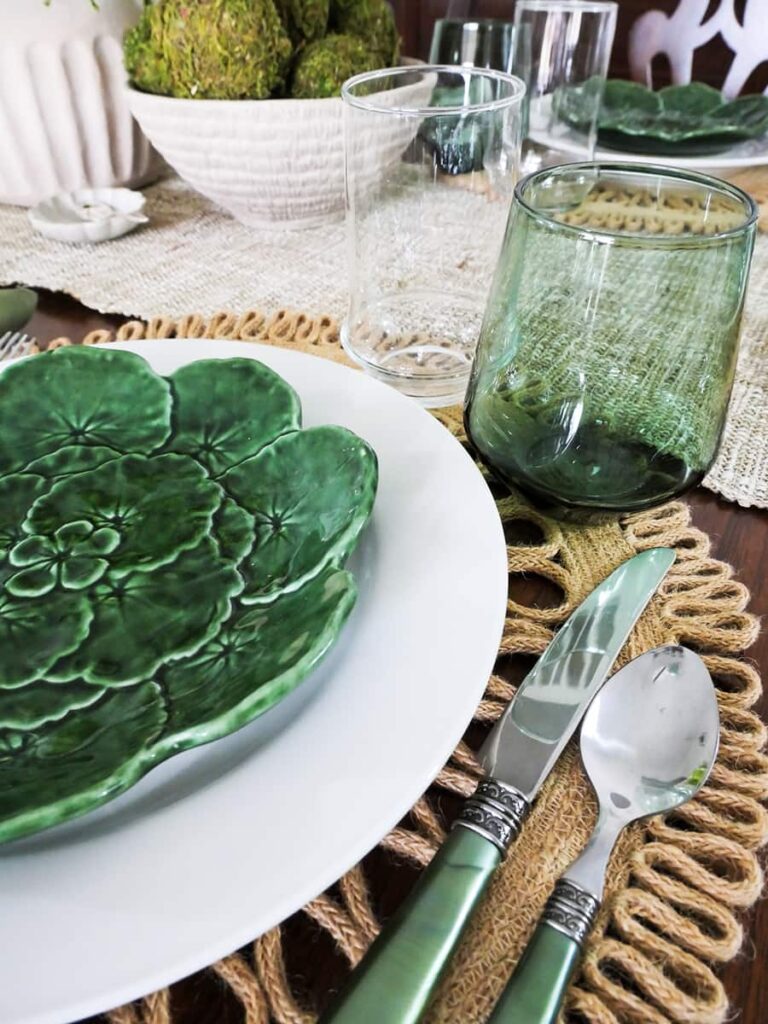 Natural St. Patrick's Day table setting close up of plates, green handle flatware and glasses.