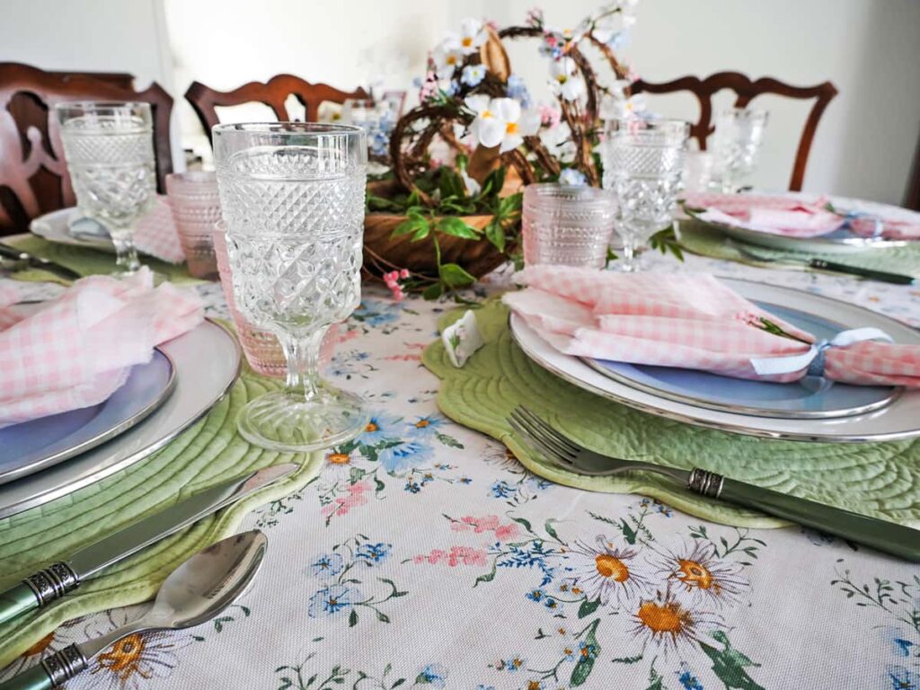 Close up of floral tablecloth with place settings in the background.