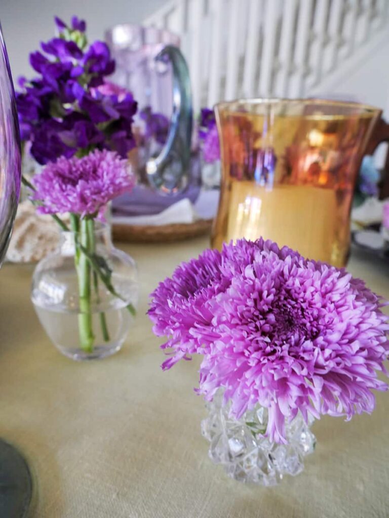 Bud vases filled with lavender colored flowers as part of the spring table centerpiece.
