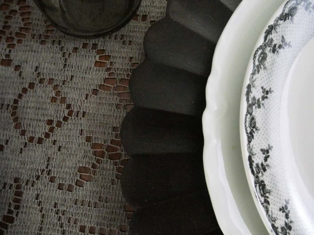 Layering of the grey lace tablecloth, black charger, dinner plate and salad plate.