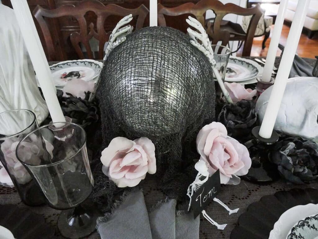 Skeleton hands on the gazing ball for the pretty Halloween tablescape.