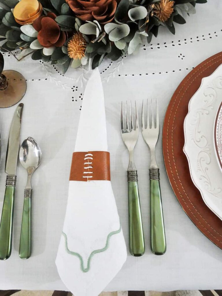 Napkin with diy napkin ring next to green handled flatware.