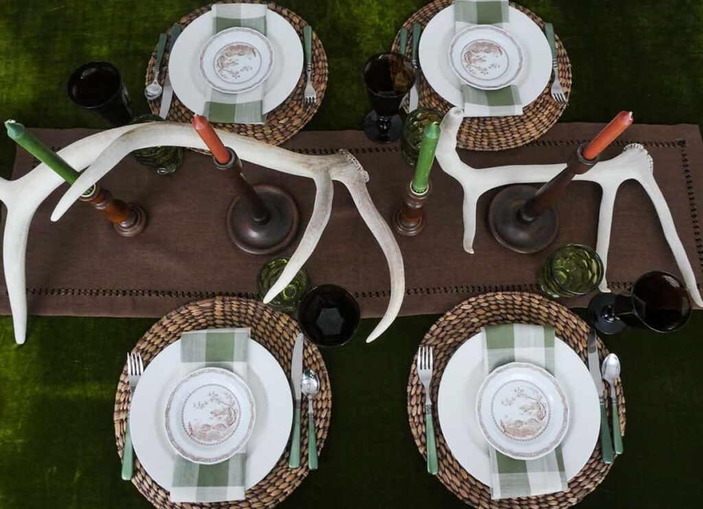 Overhead view of fall table setting with a green tablecloth and brown table runner.